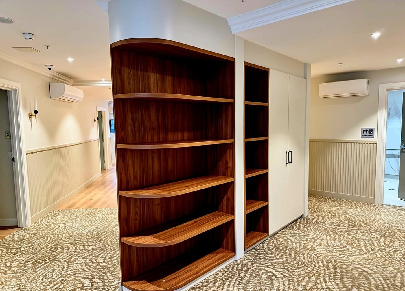 Curved walnut bookshelf in an aged care shared living area