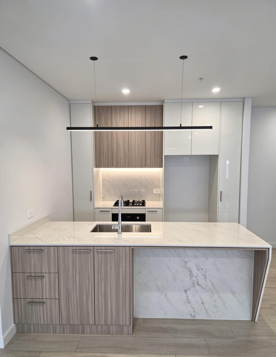 Two-tone apartment kitchen with stone waterfall island